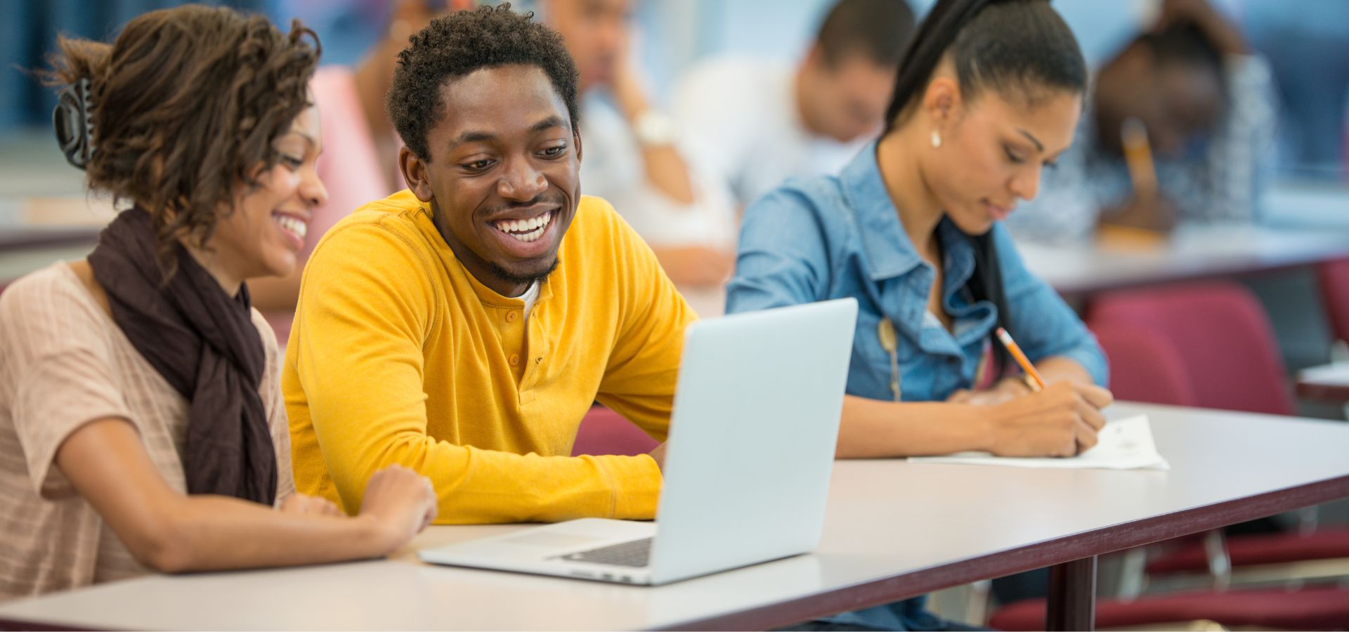 College students smiling while working together on laptop