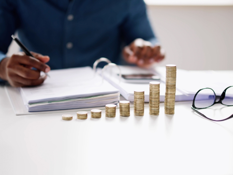 Man working on a budget with stacks of coins in front of him