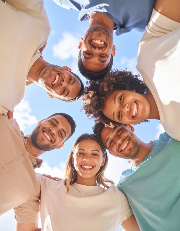 Diverse group of friends huddled in circle looking down into camera