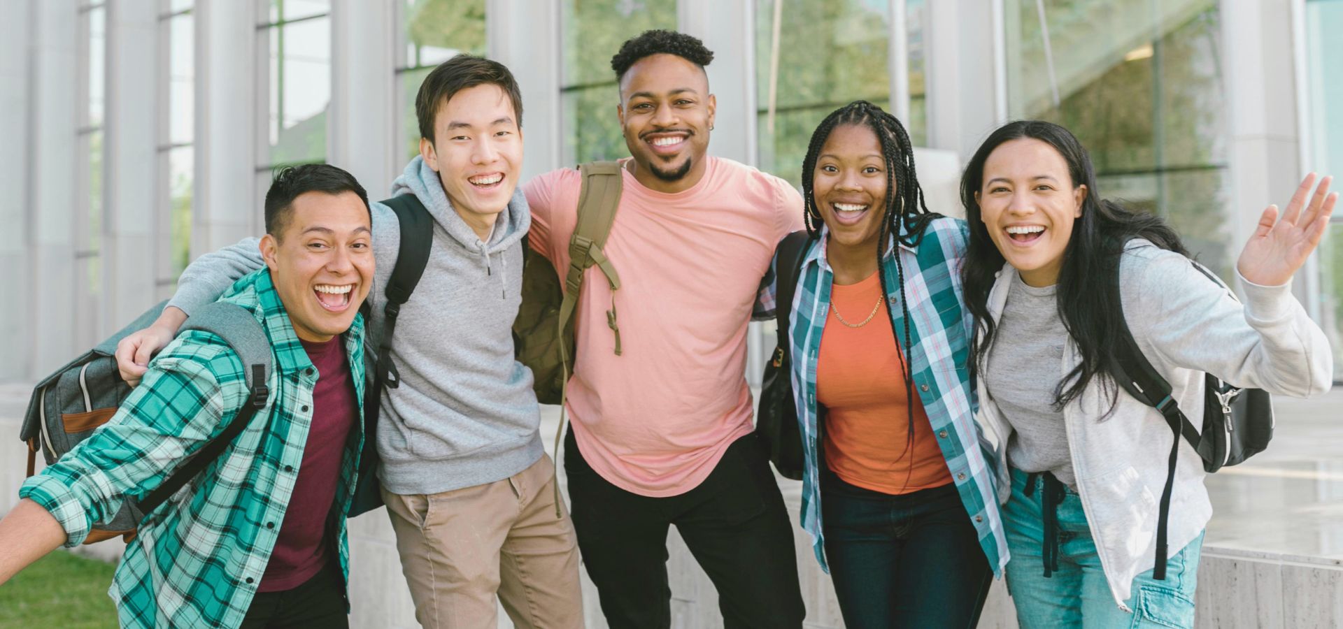 Group of five friends standing in front of college building