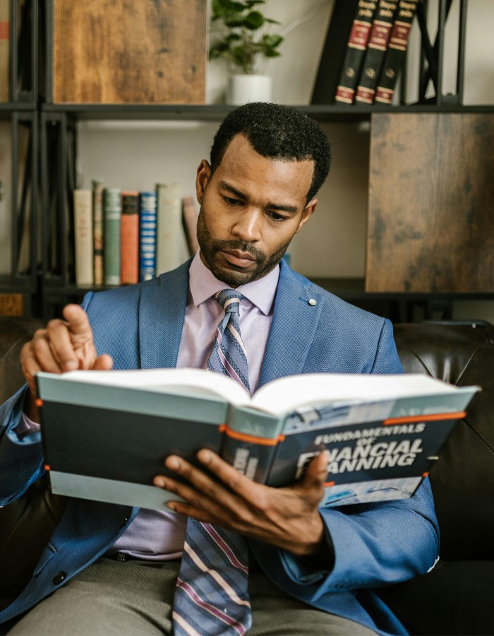 Man wearing blue suit jacket reading financial planning book