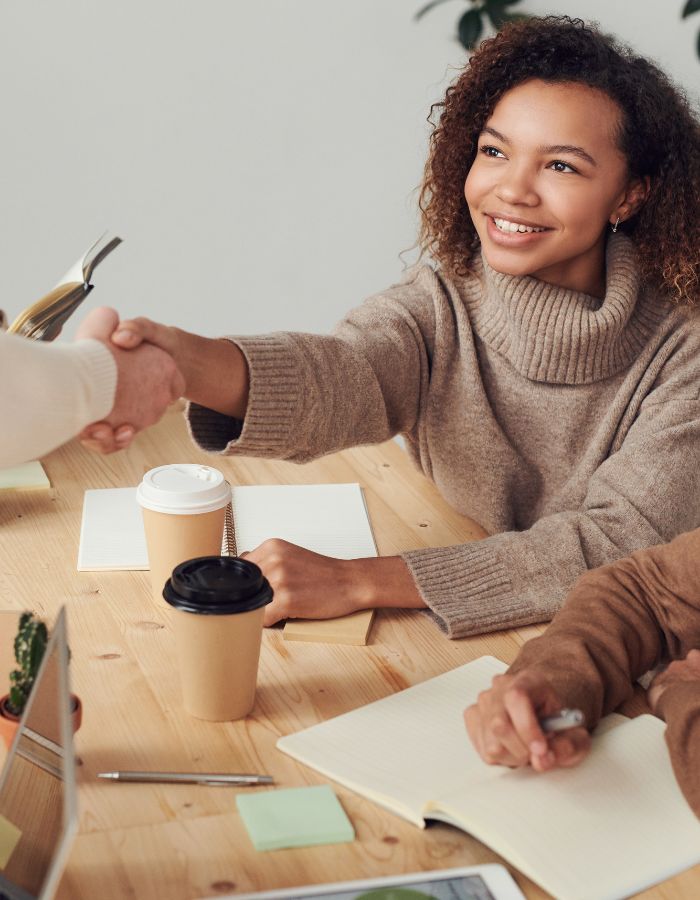 Young fair-skinned Black woman shaking hands with mentor