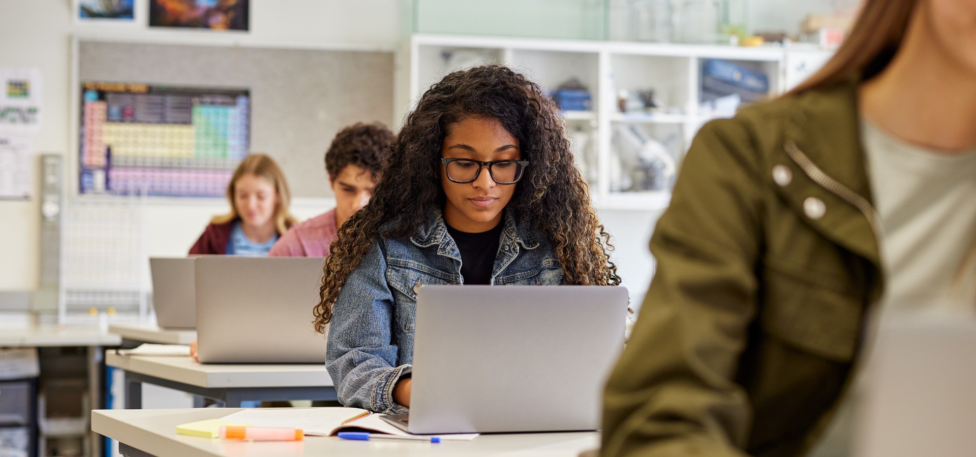 Young woman with long natural curly hair working on a laptop in class