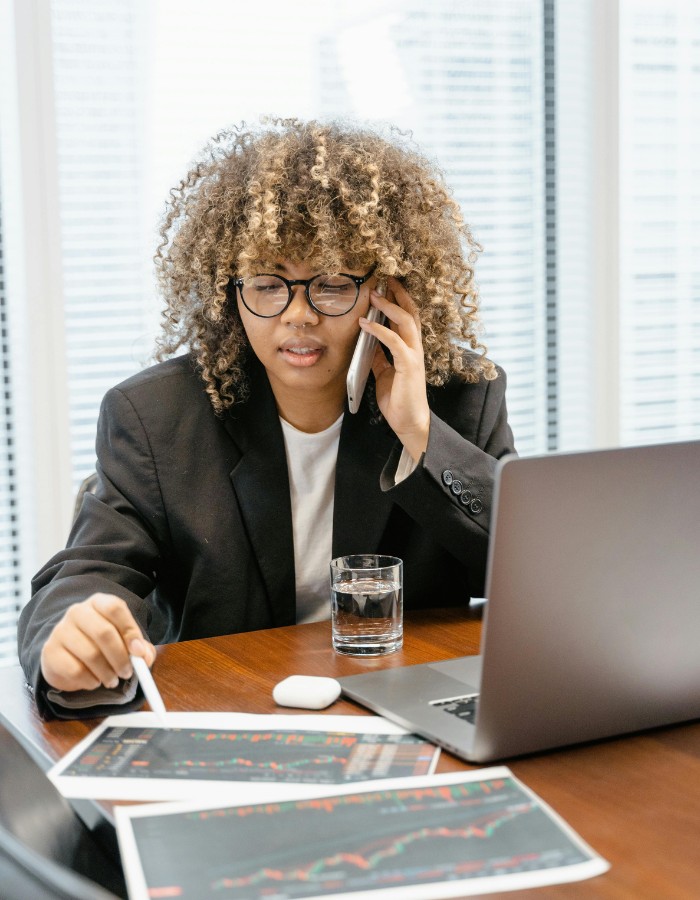 Young woman with natural curly hair on phone while looking over financial reports